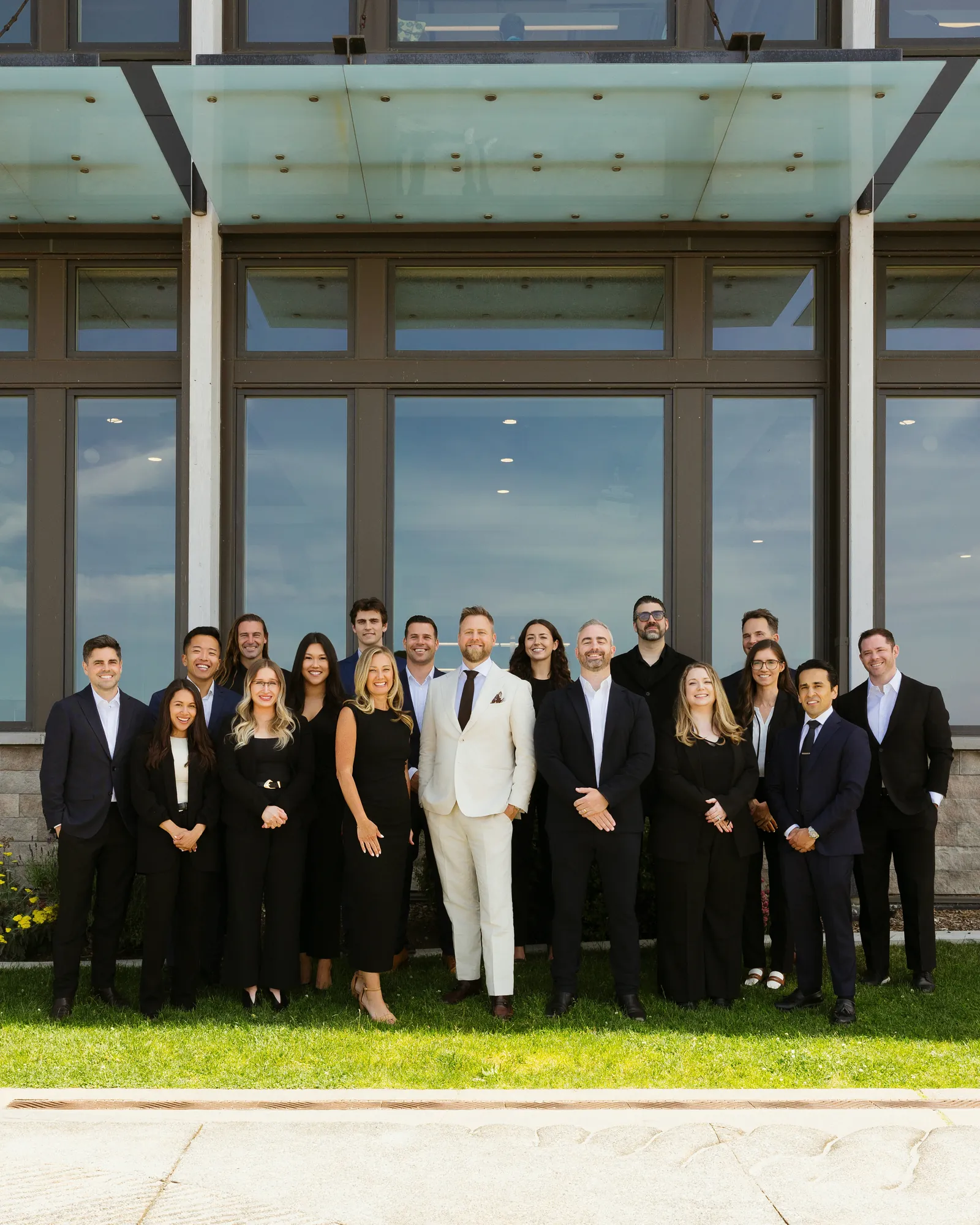The McConnell Group team in suits outside a glass office building